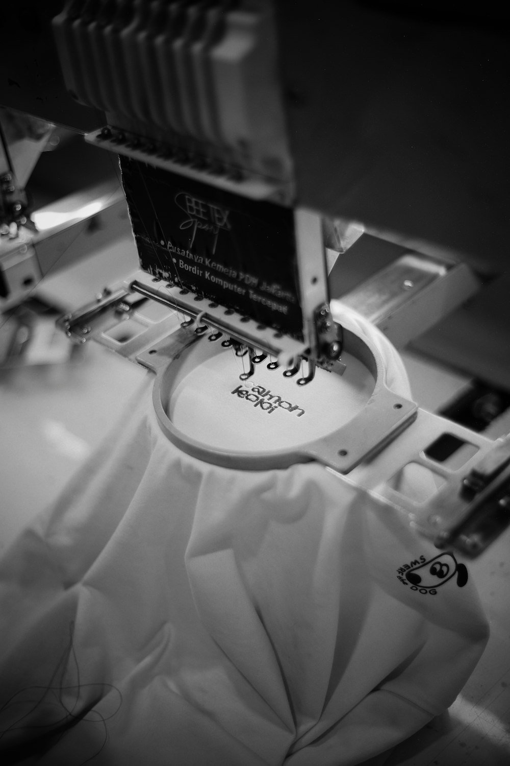 Embroidery machine stitching a logo onto white fabric